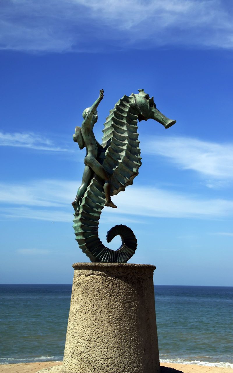 The bronze seahorse statue on the Puerto Vallarta malecon against a deep blue sky and the Pacific